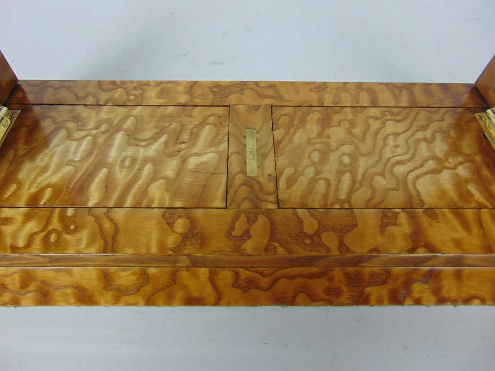 An expanding wooden book slide featuring golden burr wood veneer, folding arched ends, and a gilt brass front plate framing an oval painted porcelain cherub medallion. View VIII