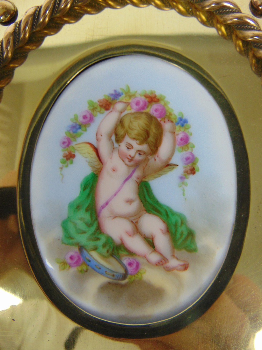 An expanding wooden book slide featuring golden burr wood veneer, folding arched ends, and a gilt brass front plate framing an oval painted porcelain cherub medallion. View IX