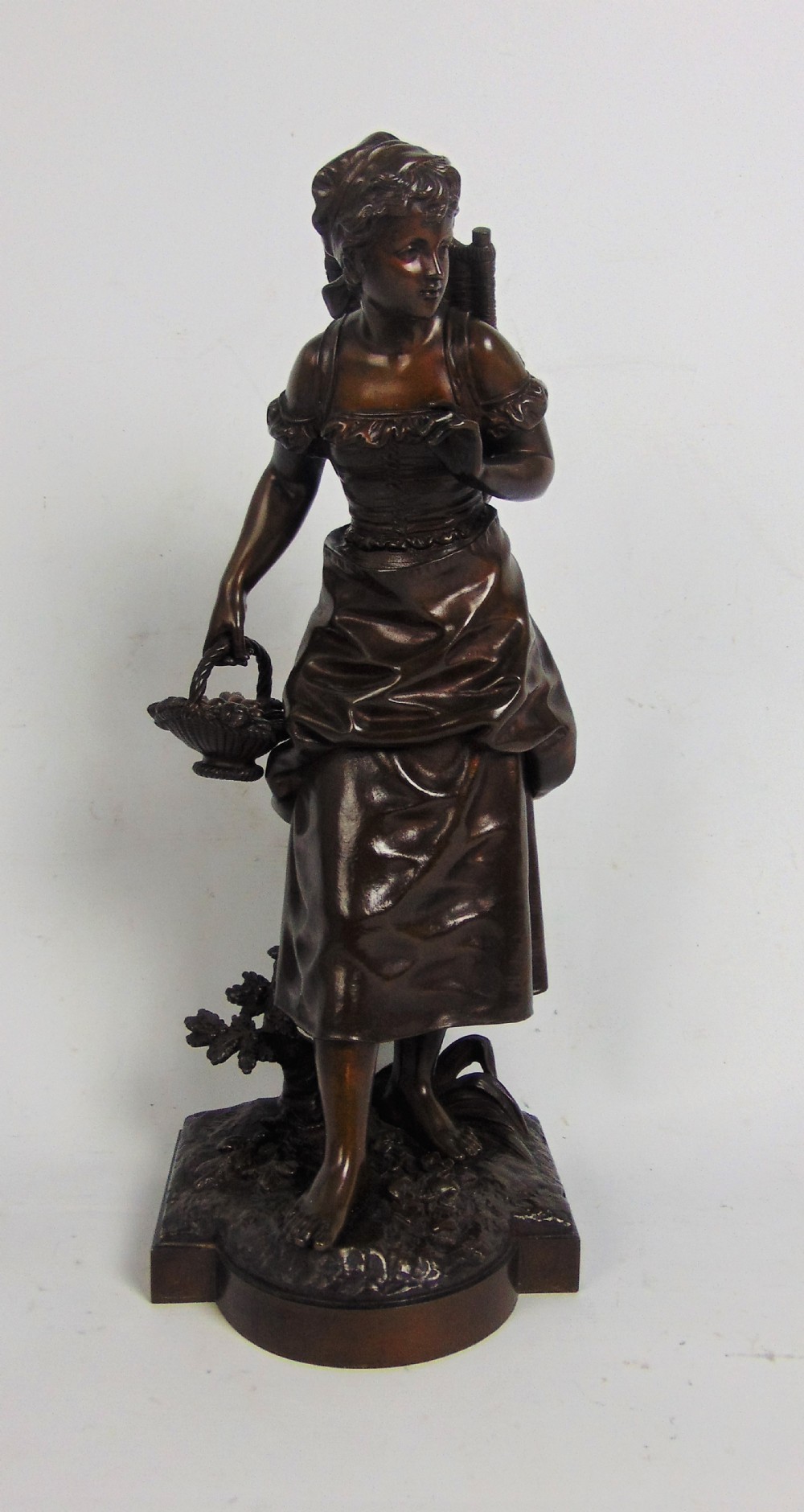 A large bronze bare footed girl collecting eggs