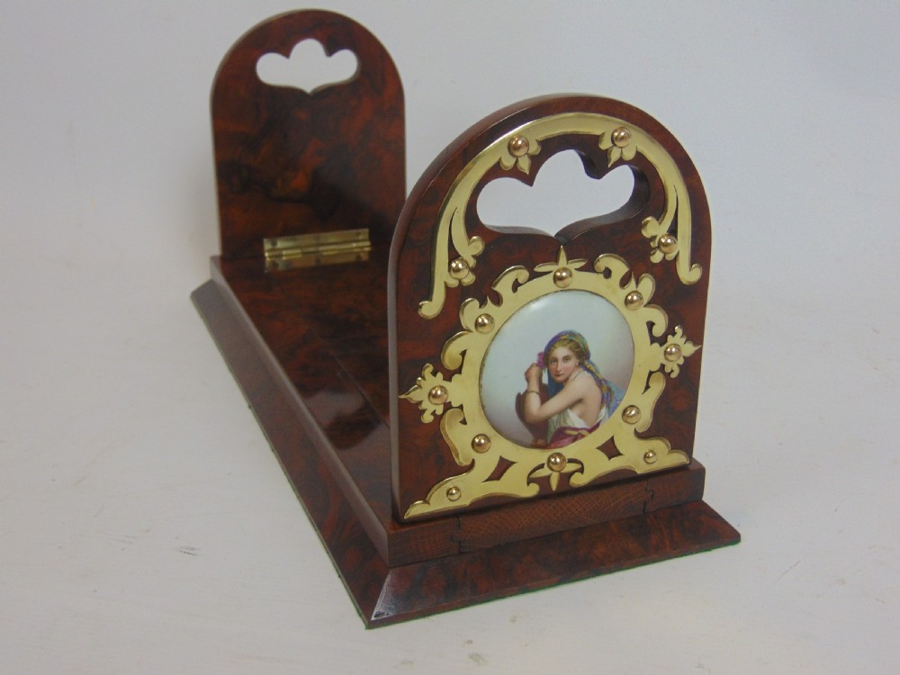 An antique burr walnut book slide featuring pierced brass strapwork with cut-out motifs and two inset circular porcelain plaques painted with female portraits. View II