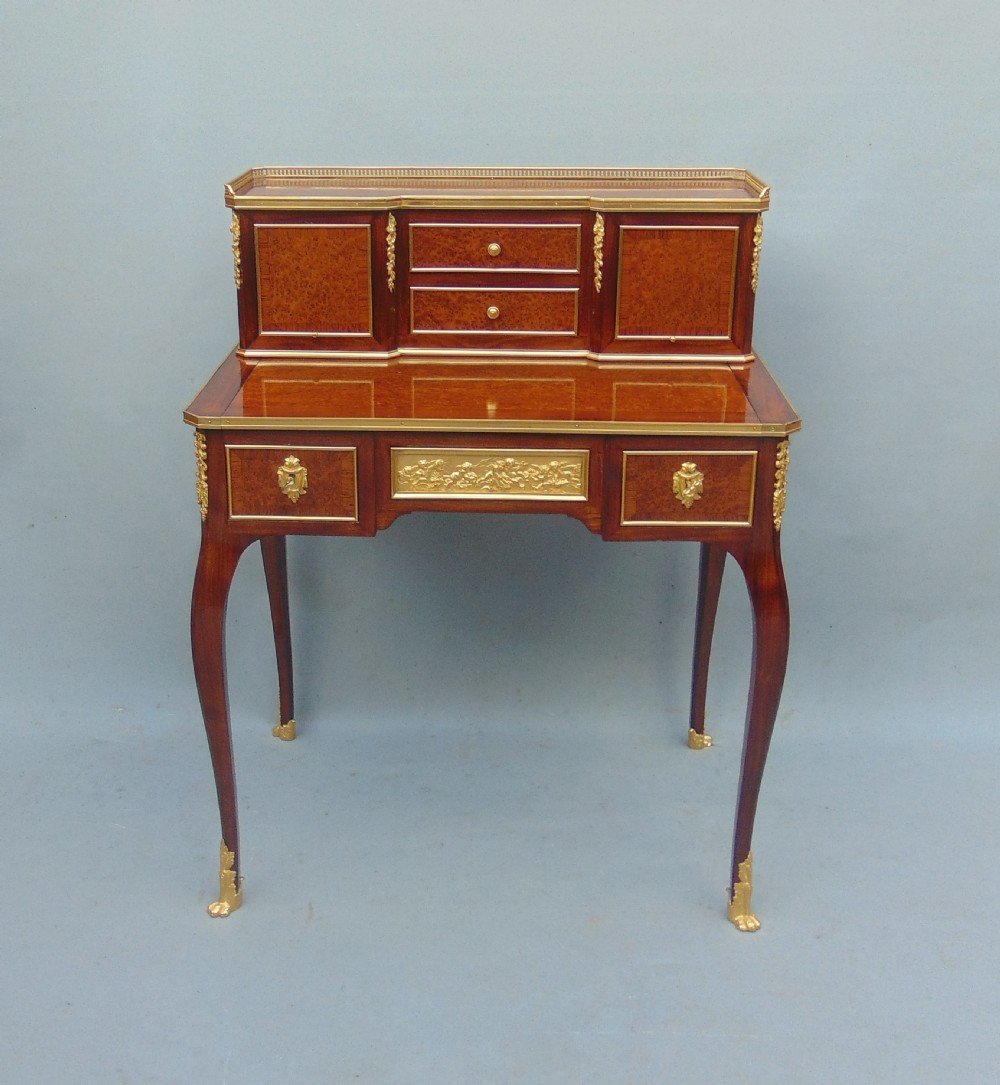 A nineteenth-century French writing desk featuring burr wood veneers, gilt bronze mounts, cabriole legs, and a raised superstructure with small drawers.