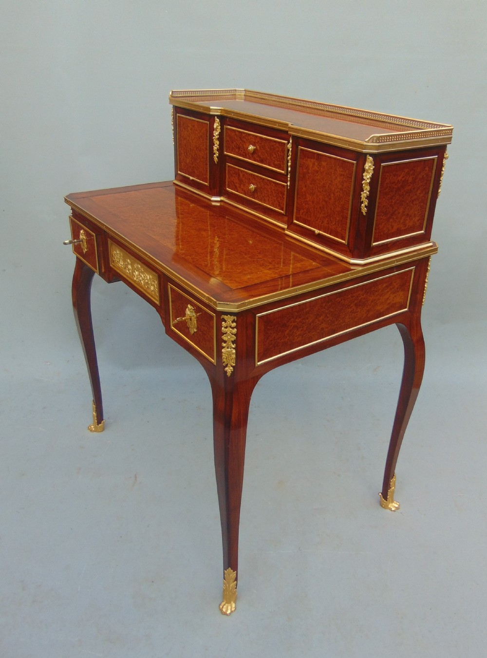 A nineteenth-century French writing desk featuring burr wood veneers, gilt bronze mounts, cabriole legs, and a raised superstructure with small drawers. View II