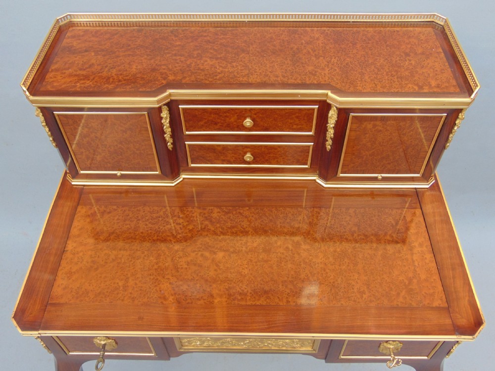 A nineteenth-century French writing desk featuring burr wood veneers, gilt bronze mounts, cabriole legs, and a raised superstructure with small drawers. View V