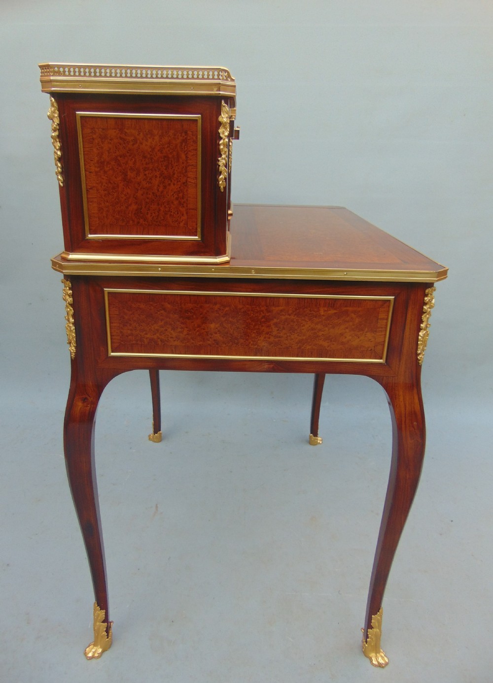 A nineteenth-century French writing desk featuring burr wood veneers, gilt bronze mounts, cabriole legs, and a raised superstructure with small drawers. View VI