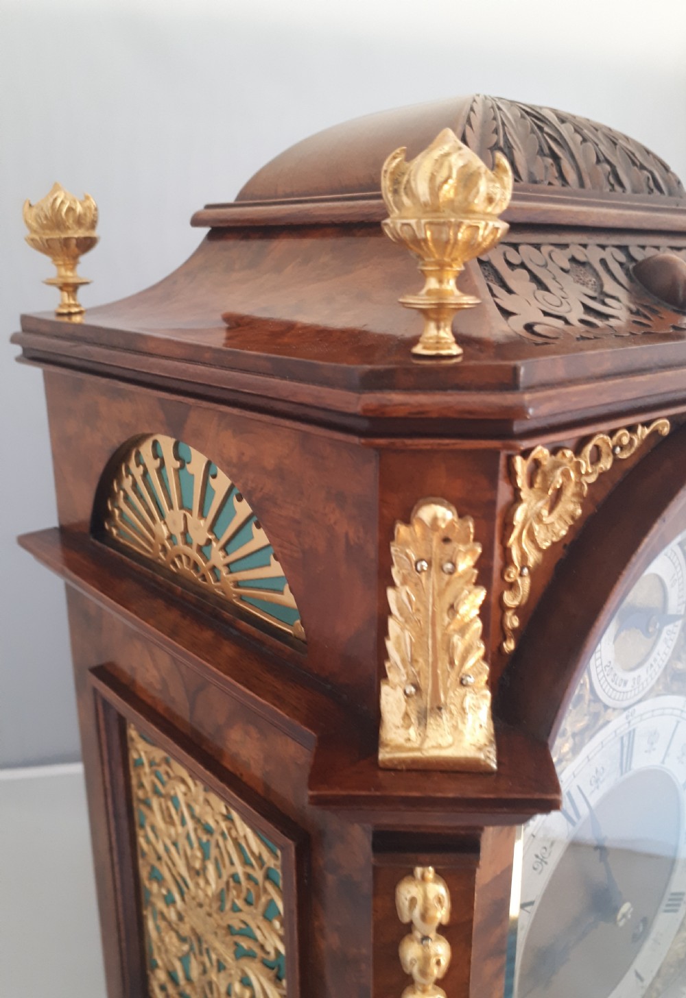 An arched burr walnut bracket clock with ornate gilt brass mounts, finials, and an intricate brass dial displaying Roman numerals. View II