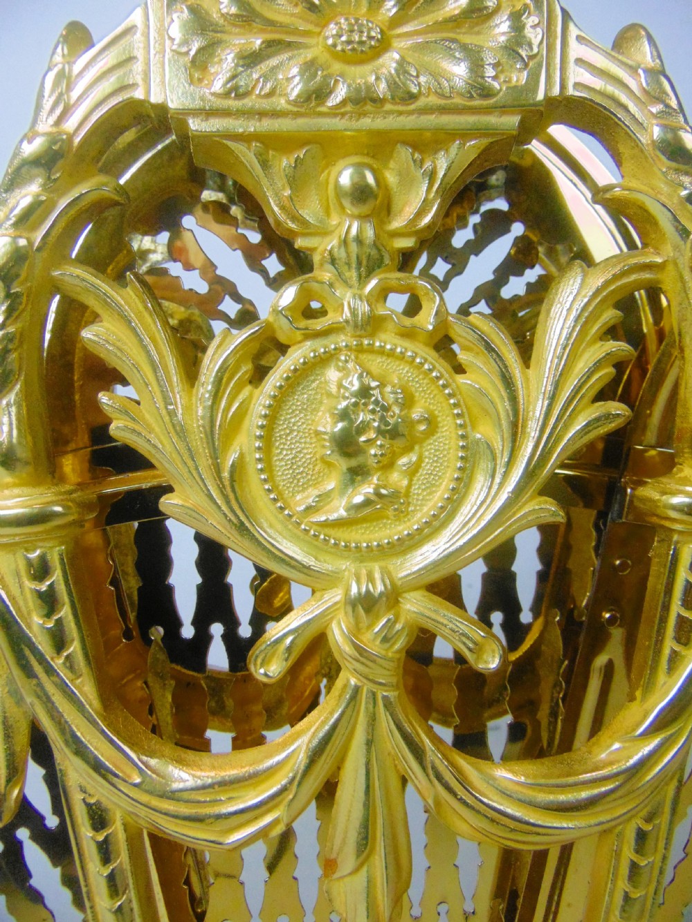 An antique French gilt bronze folding fan fire screen featuring intricate pierced lattice panels, a central crest with a relief medallion, and a weighted cast scroll base. View V