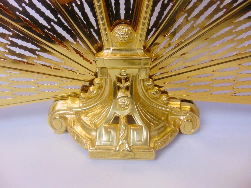 An antique French gilt bronze folding fan fire screen featuring intricate pierced lattice panels, a central crest with a relief medallion, and a weighted cast scroll base. View VI