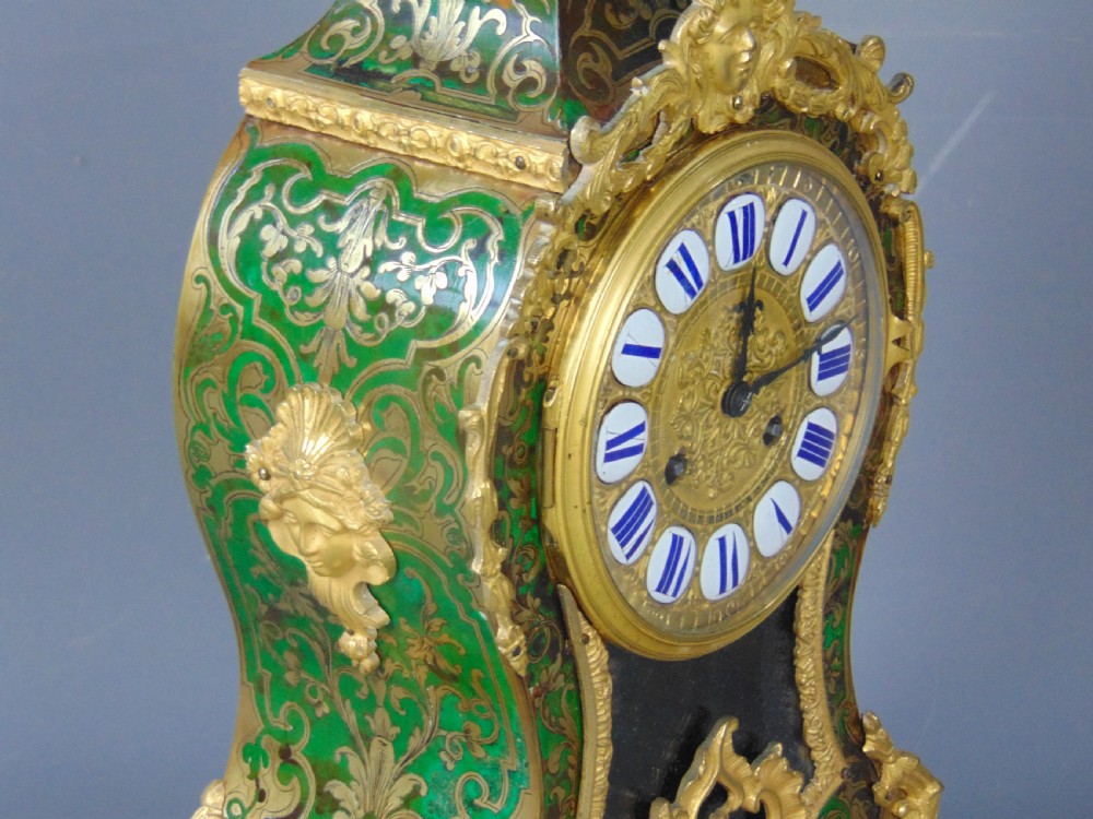 A French Rococo style green Boulle mantel clock featuring brass marquetry inlay, gilded ormolu mounts, a putto finial, and blue enamelled Roman numeral cartouches. View III