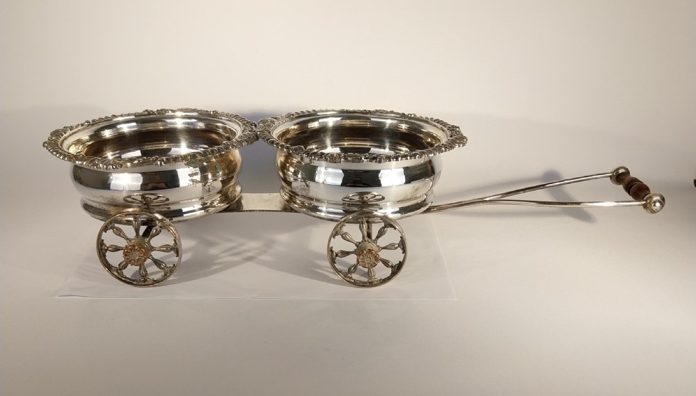 Victorian silver-plated double wine bottle trolley featuring two gadrooned coasters mounted on a wheeled frame with a long handle.