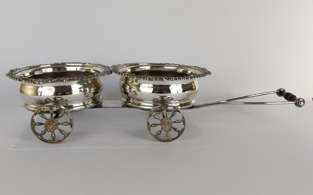 Victorian silver-plated double wine bottle trolley featuring two gadrooned coasters mounted on a wheeled frame with a long handle. View XX