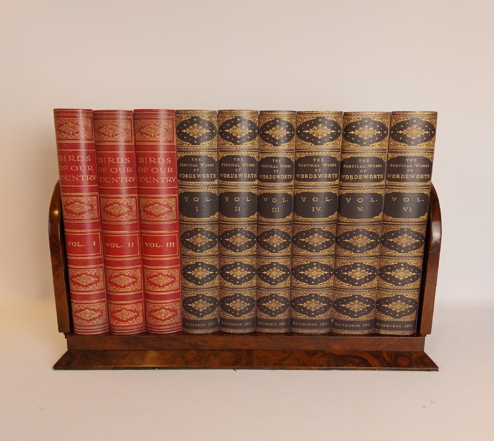 A Victorian burr walnut sliding book slide features pierced brass mounts, decorative studs, and a central painted porcelain plaque. View V