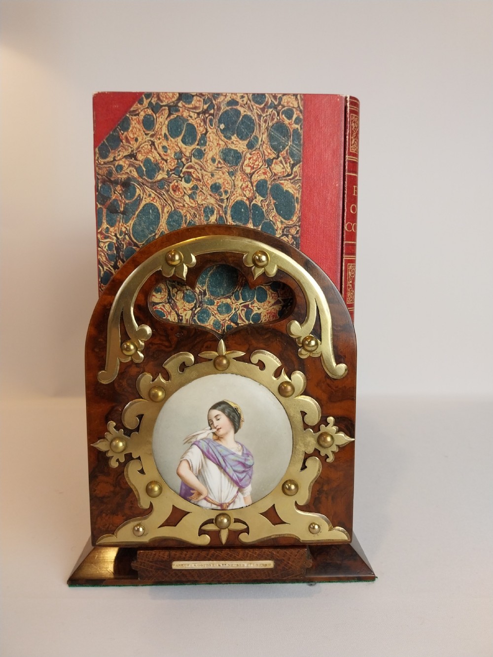 A Victorian burr walnut sliding book slide features pierced brass mounts, decorative studs, and a central painted porcelain plaque. View VII