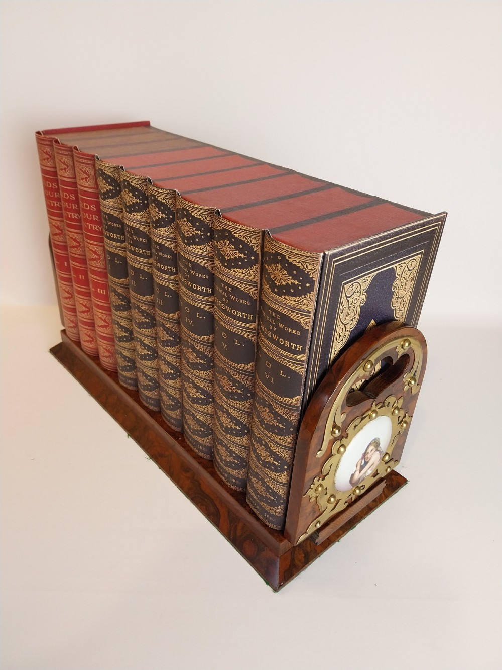 A Victorian burr walnut sliding book slide features pierced brass mounts, decorative studs, and a central painted porcelain plaque. View VIII