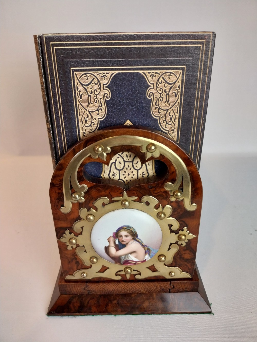 A Victorian burr walnut sliding book slide features pierced brass mounts, decorative studs, and a central painted porcelain plaque. View IX
