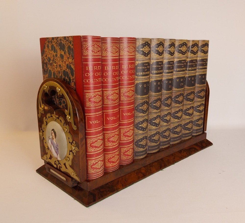 A Victorian burr walnut sliding book slide features pierced brass mounts, decorative studs, and a central painted porcelain plaque. View XI