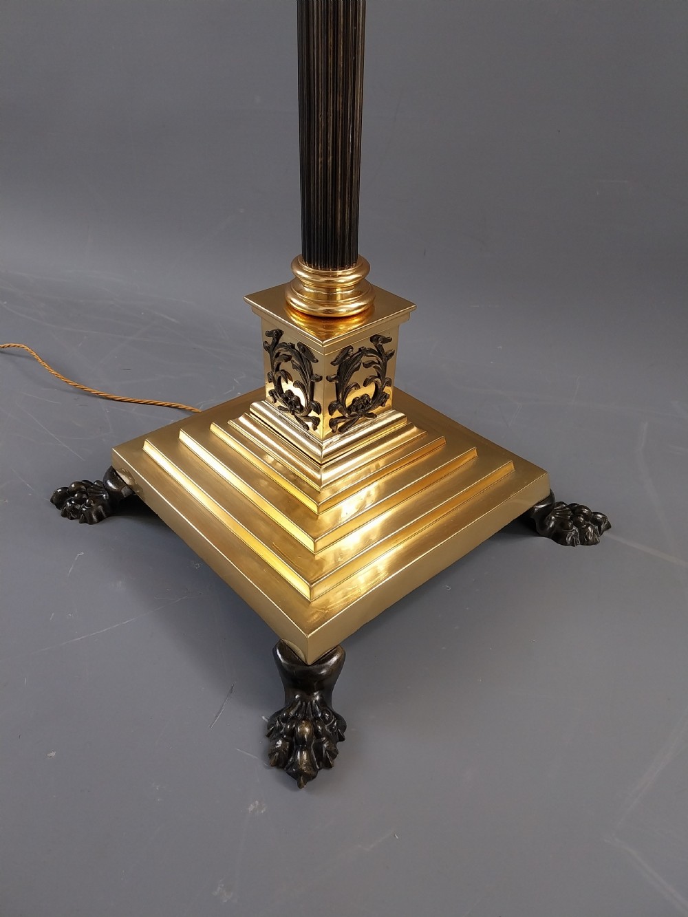 An antique Neoclassical gilt bronze floor standard lamp featuring a fluted dark column, Corinthian capital, stepped square plinth base on claw feet, and a cream fringed shade. View V