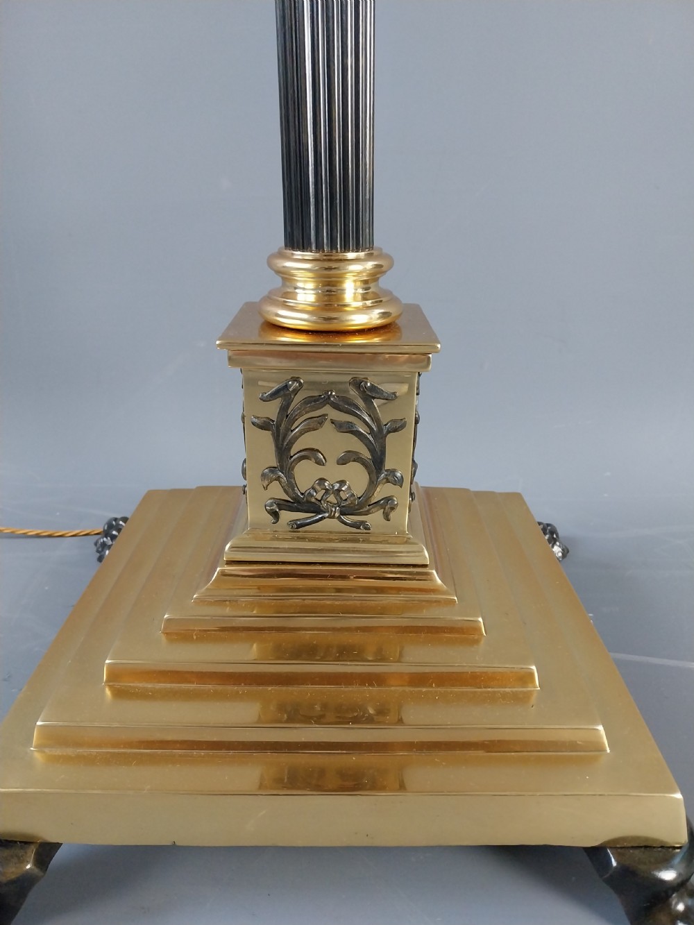 An antique Neoclassical gilt bronze floor standard lamp featuring a fluted dark column, Corinthian capital, stepped square plinth base on claw feet, and a cream fringed shade. View IX