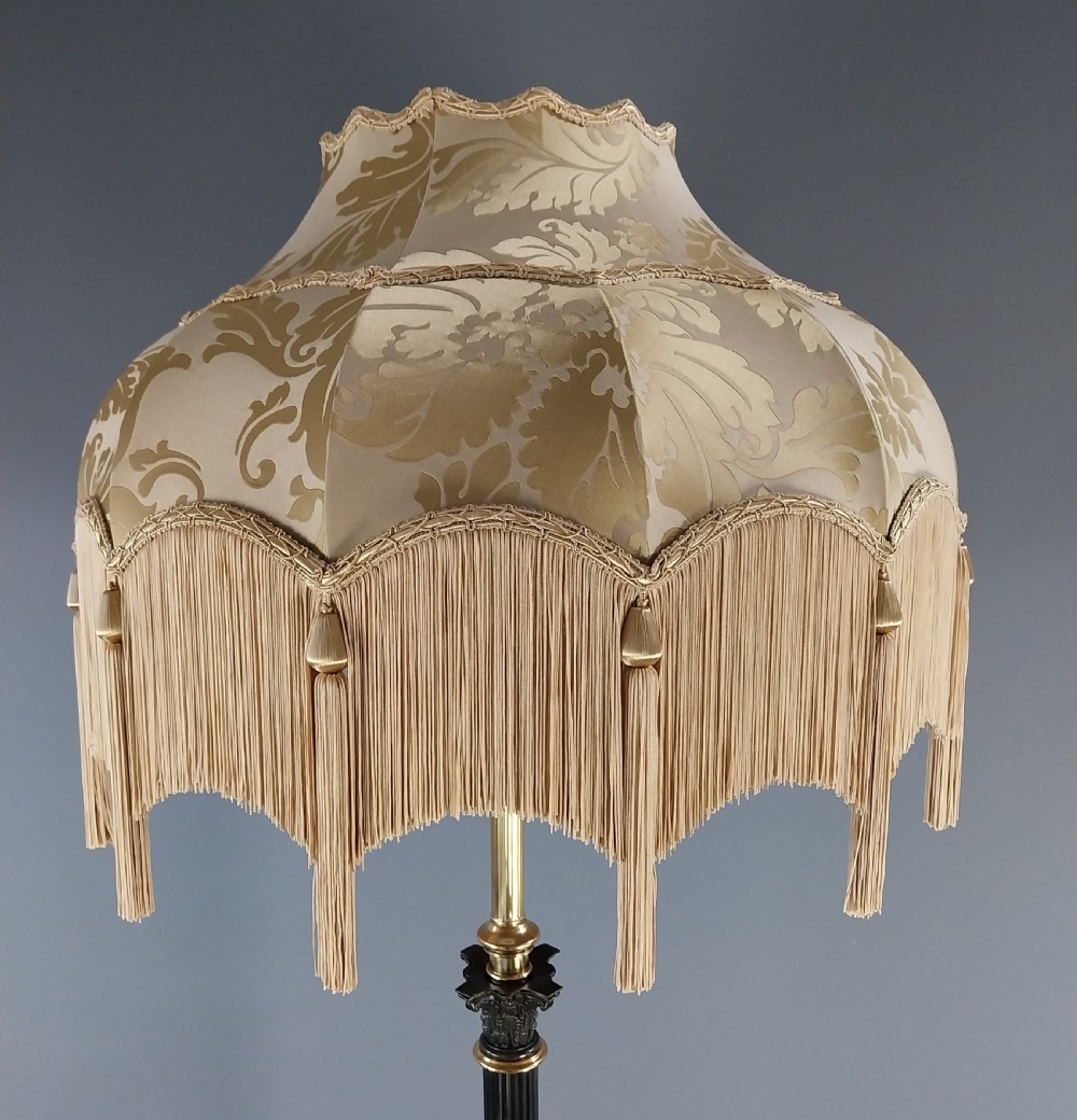 An antique Neoclassical gilt bronze floor standard lamp featuring a fluted dark column, Corinthian capital, stepped square plinth base on claw feet, and a cream fringed shade. View XIII