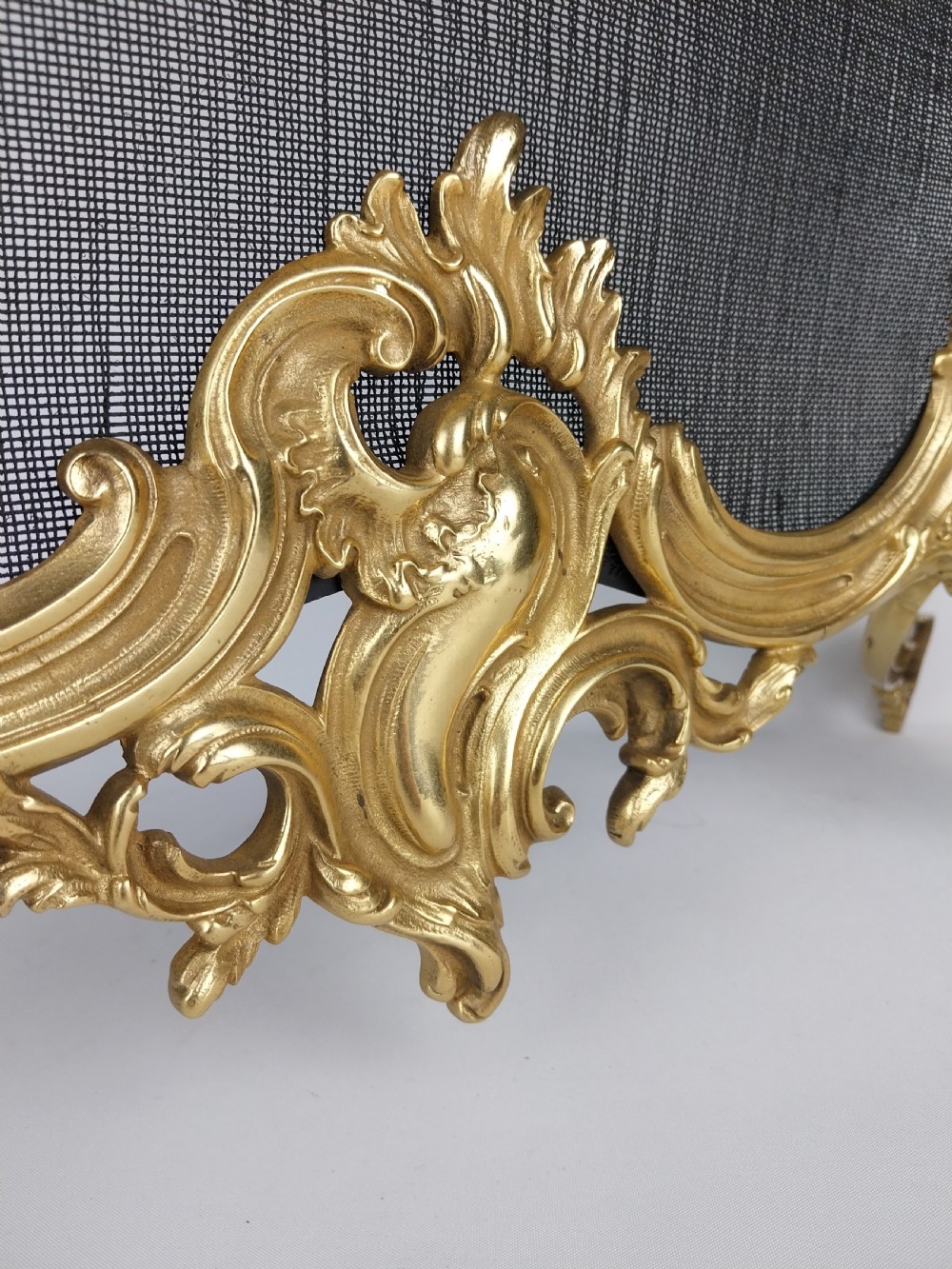 A French Louis XV style gilt bronze fire screen featuring an asymmetrical rocaille frame, central cherub motif, and woven metal mesh. View IX