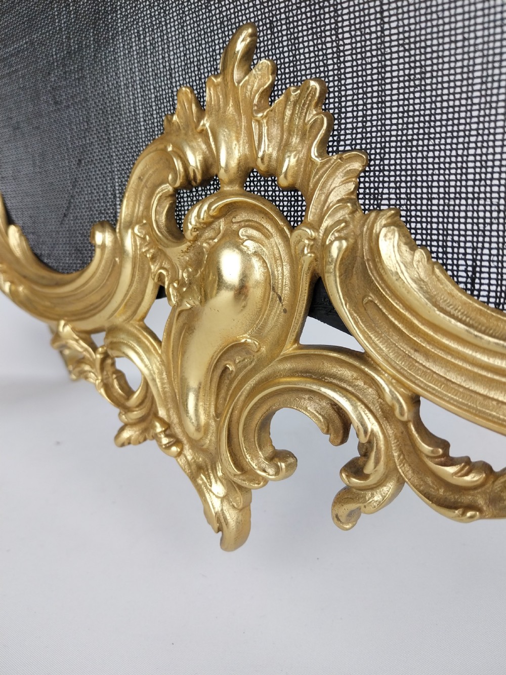 A French Louis XV style gilt bronze fire screen featuring an asymmetrical rocaille frame, central cherub motif, and woven metal mesh. View XIII