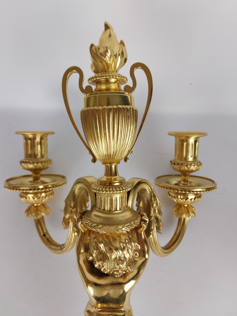A pair of French Louis XVI style gilt bronze wall sconces featuring central cherub figures holding two curving candle arms topped with urn finials. View VI