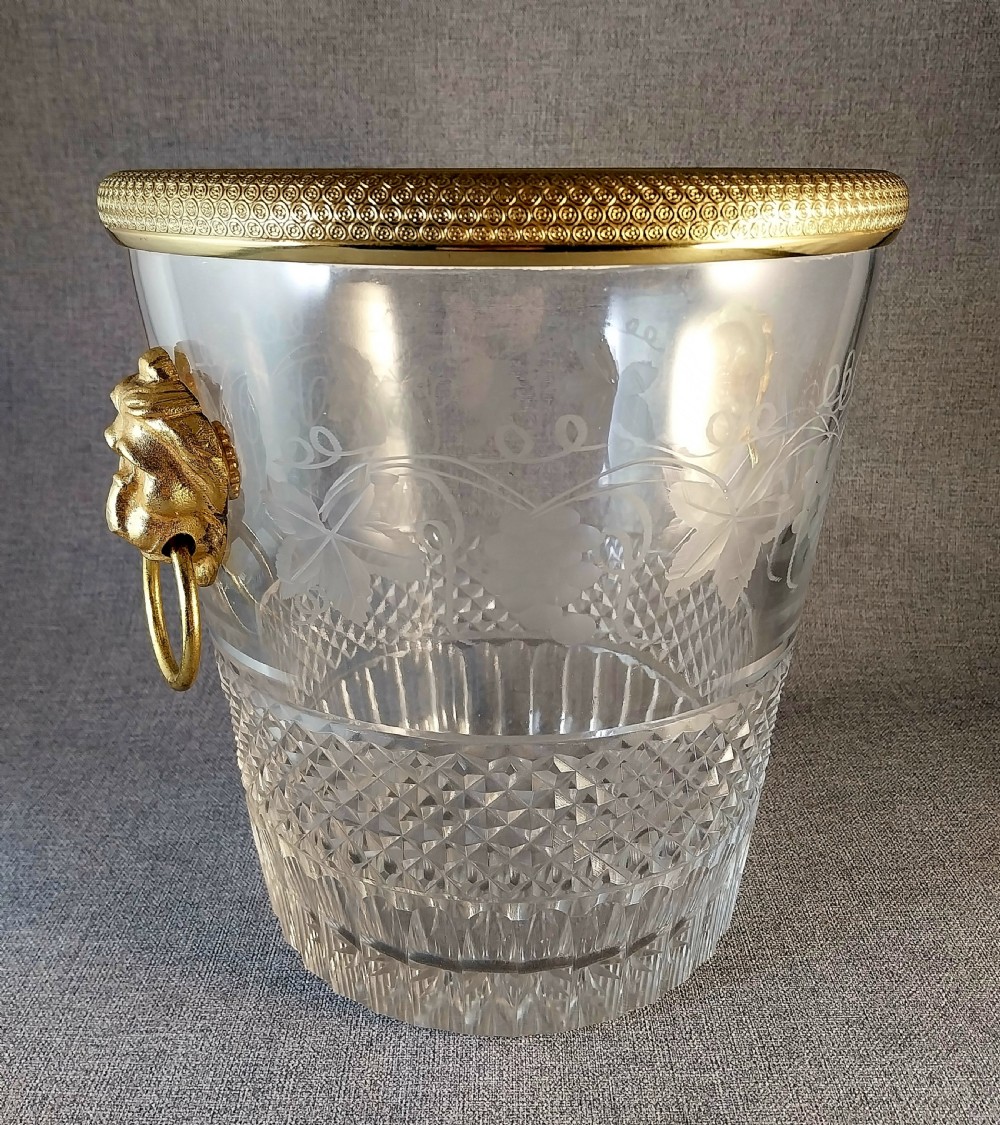 A clear cut glass champagne cooler with etched grapevine detailing, diamond-faceted lower glass, and gilt bronze lion-head ring handles. View II