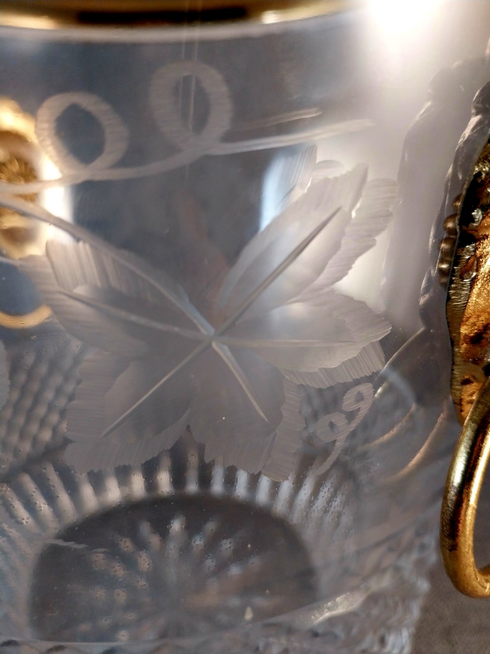 A clear cut glass champagne cooler with etched grapevine detailing, diamond-faceted lower glass, and gilt bronze lion-head ring handles. View XII