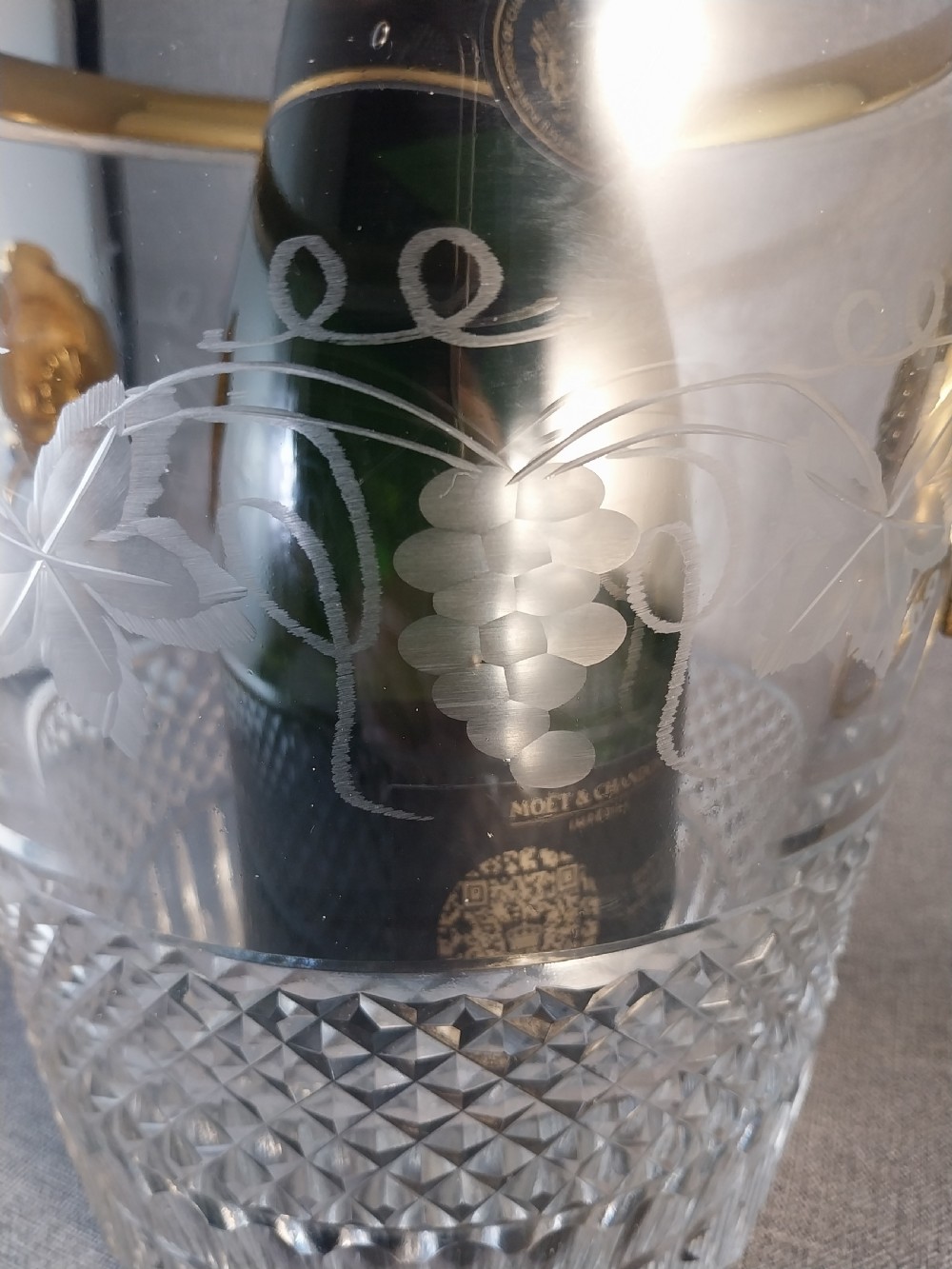 A clear cut glass champagne cooler with etched grapevine detailing, diamond-faceted lower glass, and gilt bronze lion-head ring handles. View XVIII