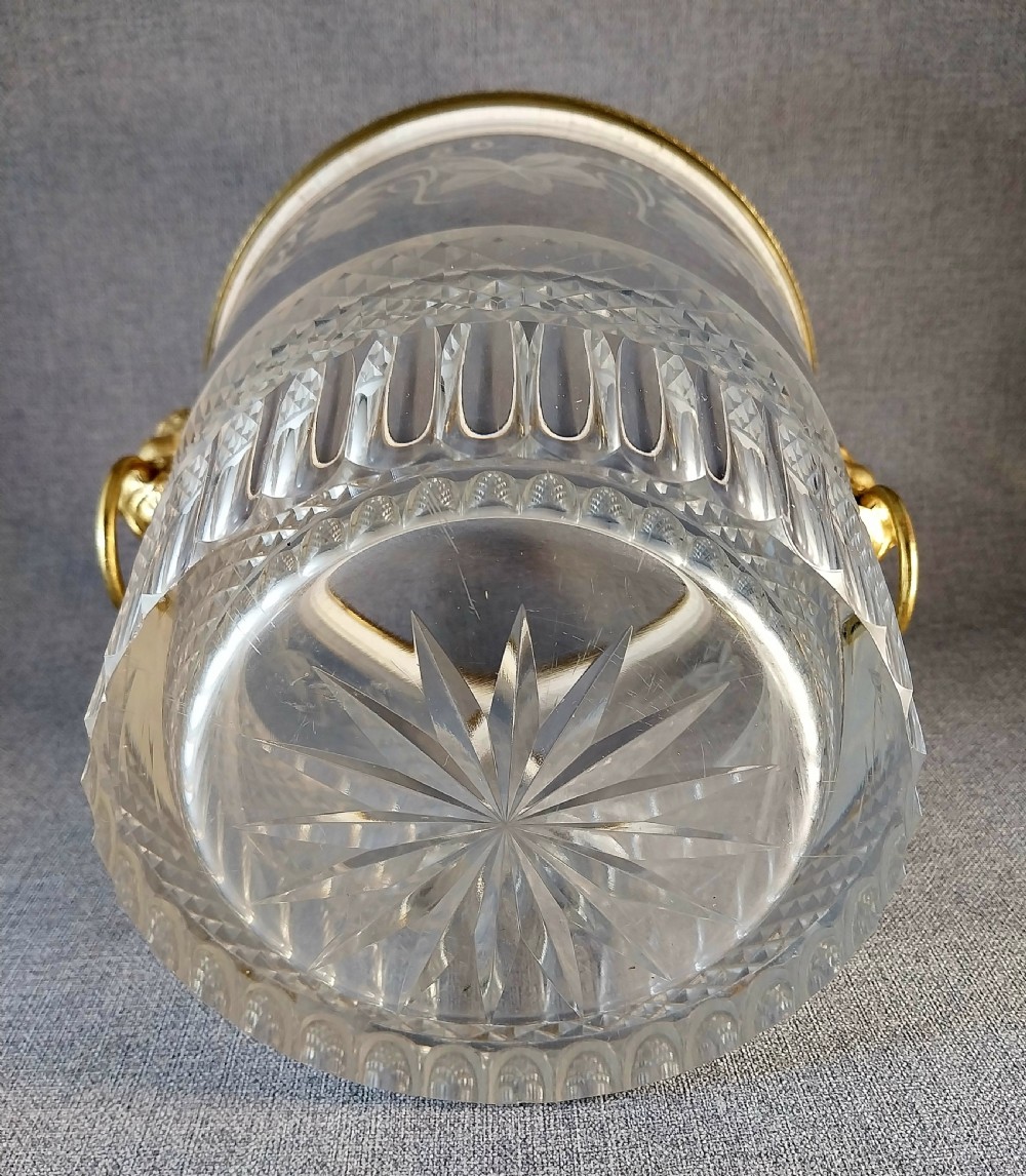 A clear cut glass champagne cooler with etched grapevine detailing, diamond-faceted lower glass, and gilt bronze lion-head ring handles. View XX
