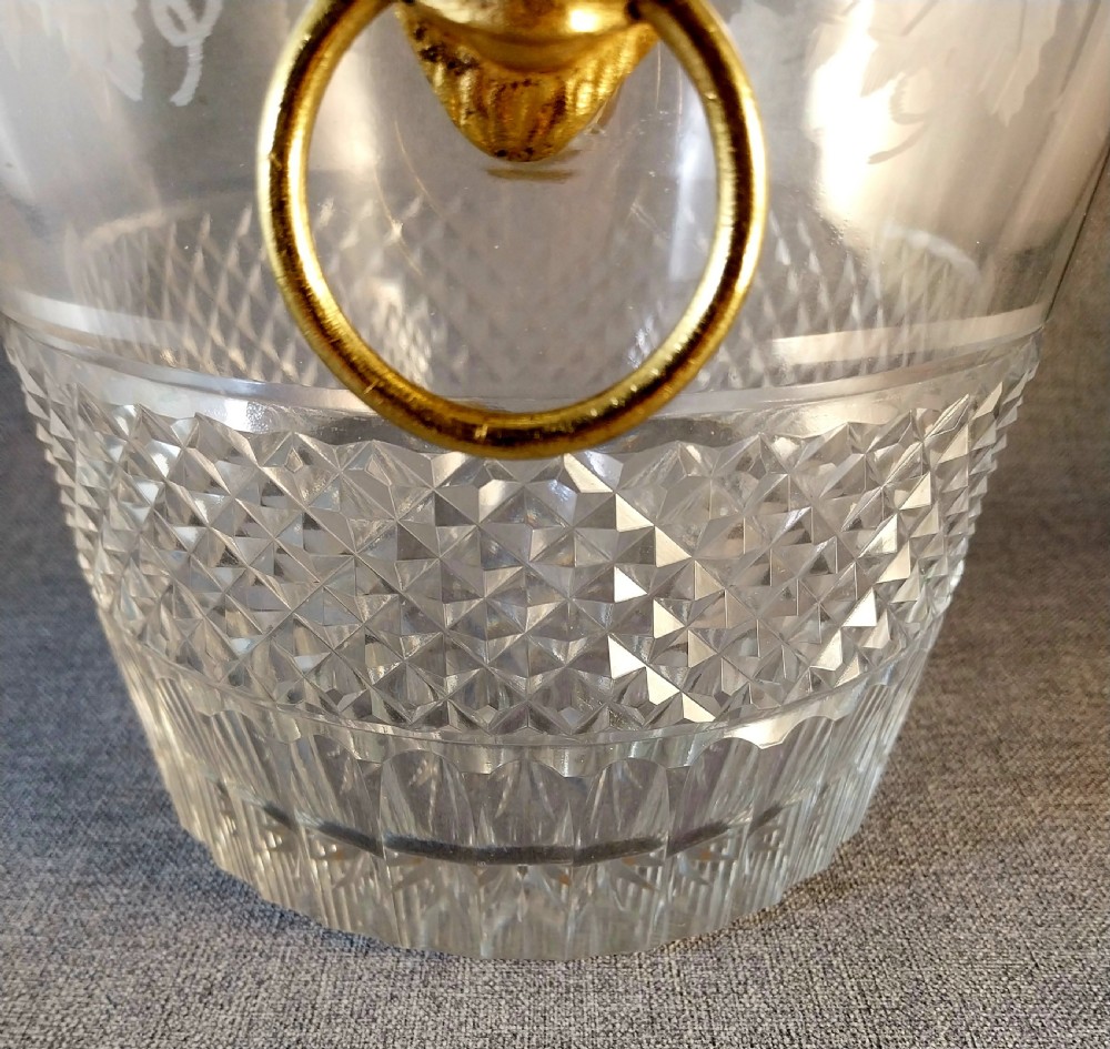 A clear cut glass champagne cooler with etched grapevine detailing, diamond-faceted lower glass, and gilt bronze lion-head ring handles. View XXVII