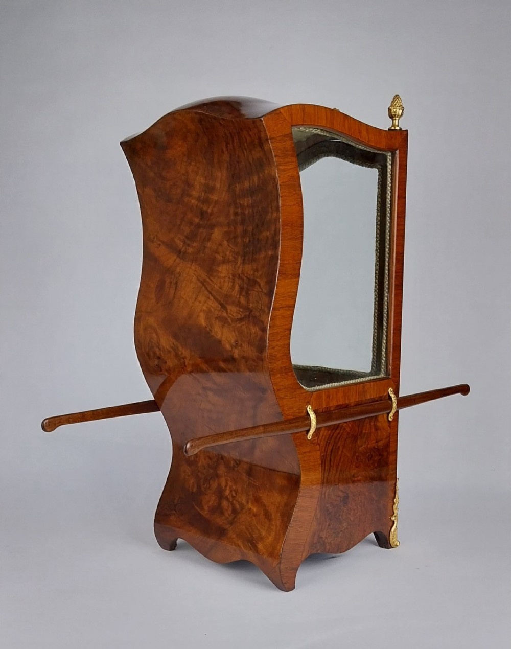 A French tabletop sedan chair vitrine cabinet crafted from polished brown wood veneer with gilt-bronze mounts, glazed side panels, removable carrying poles, and a silk damask interior. View IV