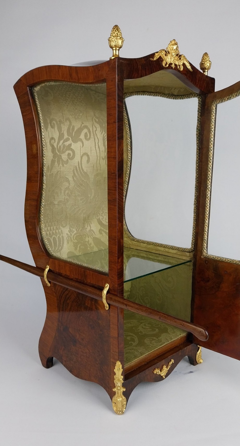 A French tabletop sedan chair vitrine cabinet crafted from polished brown wood veneer with gilt-bronze mounts, glazed side panels, removable carrying poles, and a silk damask interior. View VIII