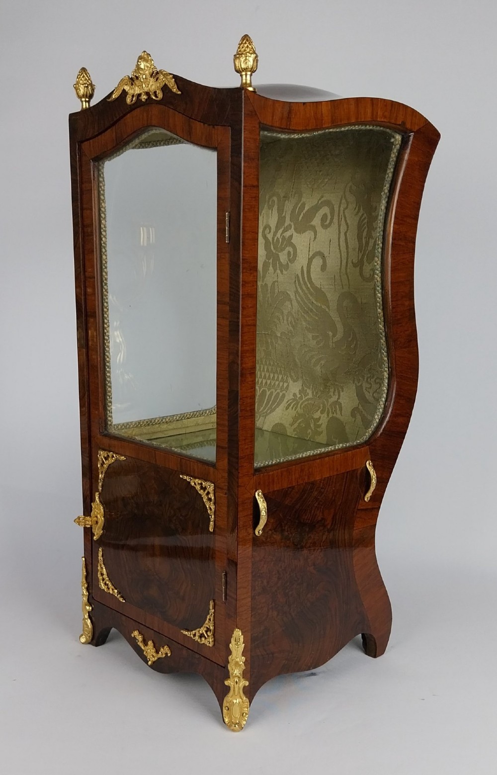 A French tabletop sedan chair vitrine cabinet crafted from polished brown wood veneer with gilt-bronze mounts, glazed side panels, removable carrying poles, and a silk damask interior. View X