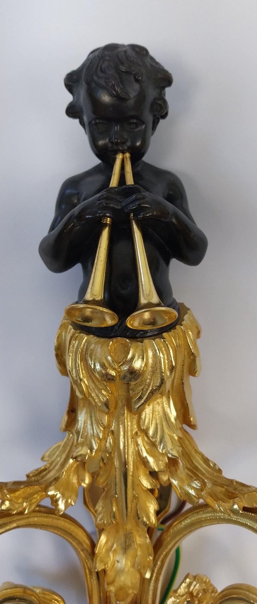 A pair of French gilt and dark patinated bronze two-branch wall sconces featuring central figures holding musical instruments. View X