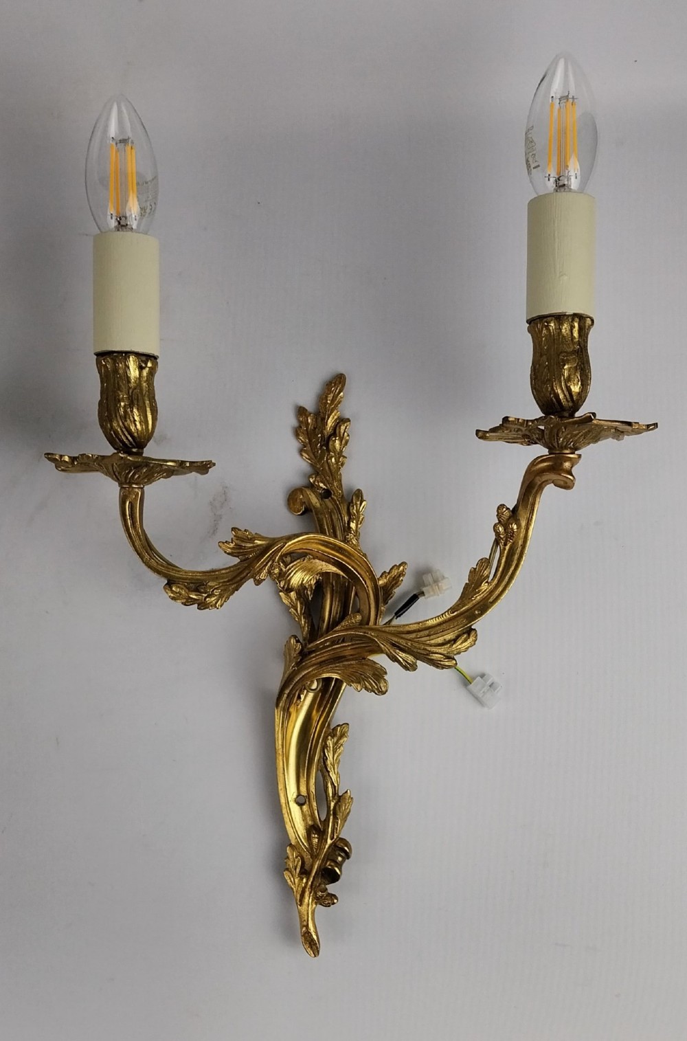A pair of French Rococo style gilt bronze two-arm wall sconces featuring scrolling acanthus leaf backplates and candle-style sockets. View II