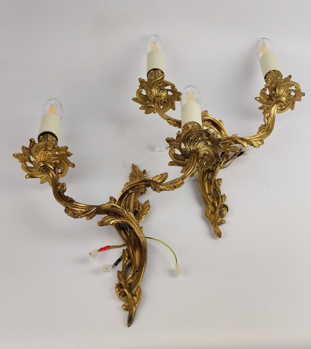 A pair of French Rococo style gilt bronze two-arm wall sconces featuring scrolling acanthus leaf backplates and candle-style sockets. View III