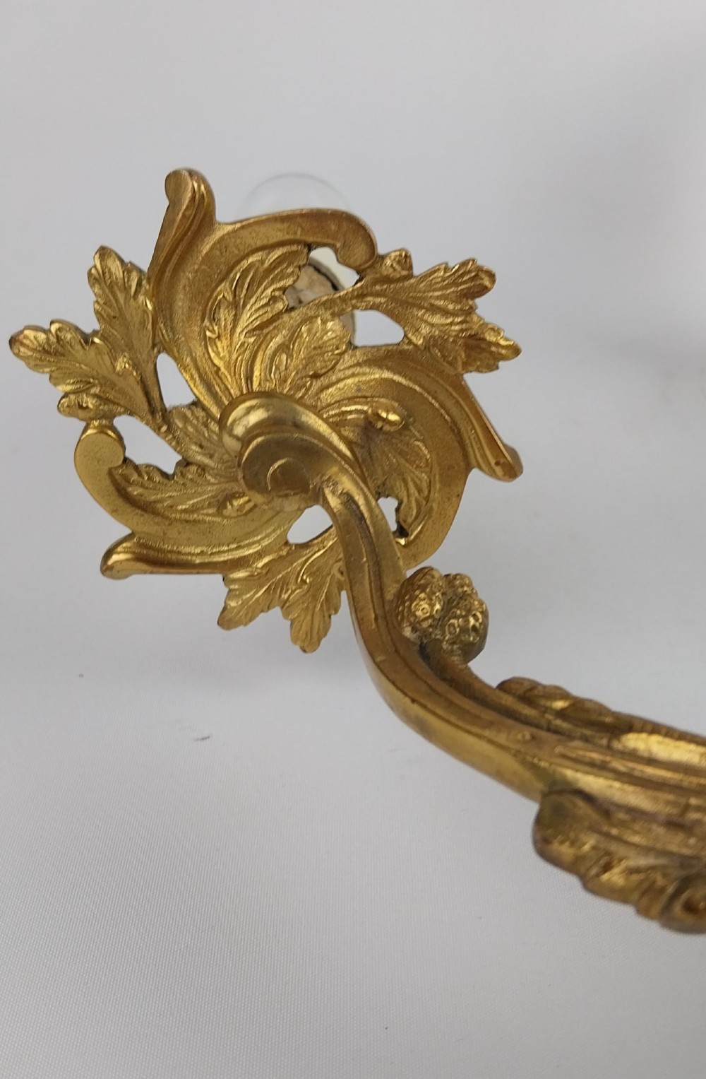 A pair of French Rococo style gilt bronze two-arm wall sconces featuring scrolling acanthus leaf backplates and candle-style sockets. View IV
