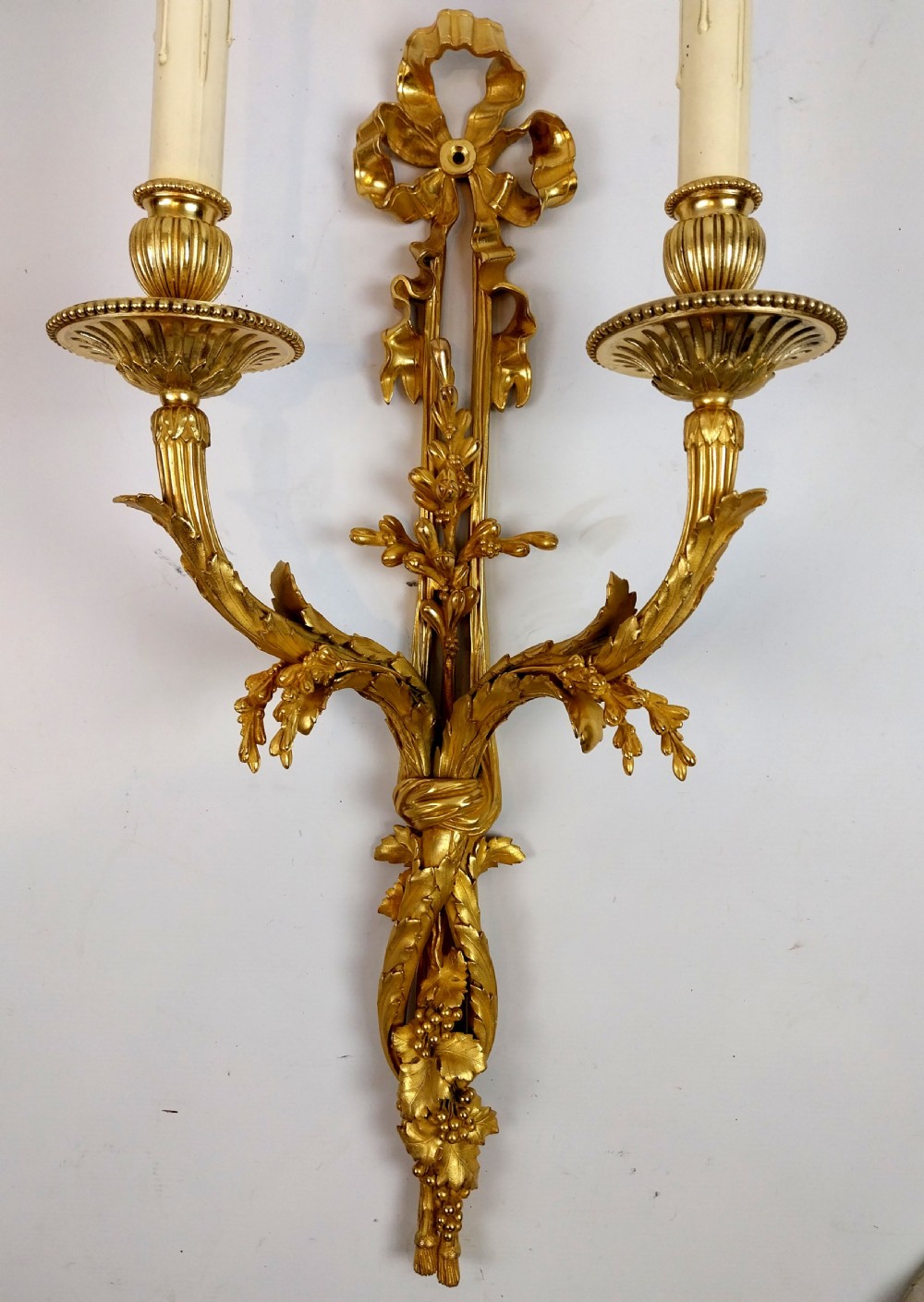A pair of antique French gilt bronze two-arm wall sconces decorated with top ribbon bow crests and foliate scroll branches. View IV