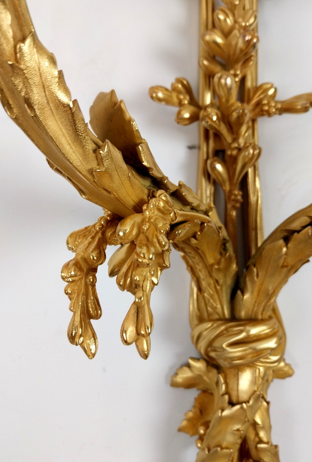 A pair of antique French gilt bronze two-arm wall sconces decorated with top ribbon bow crests and foliate scroll branches. View V