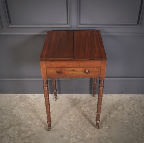 fig 1. An antique Regency mahogany writing table featuring an adjustable leather-lined ratcheted reading slope, drop side flaps, a single drawer, and ring-turned legs with brass castors.