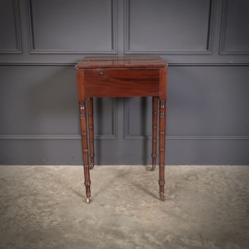 fig 2. An antique Regency mahogany writing table featuring an adjustable leather-lined ratcheted reading slope, drop side flaps, a single drawer, and ring-turned legs with brass castors.