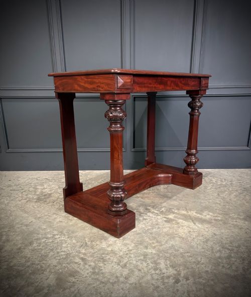 fig 1. An antique dark mahogany console table featuring carved turned columns and a solid plinth base.
