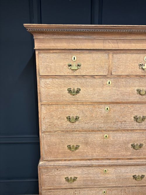 fig 1. An 18th-century bleached oak chest on chest with stacked upper and lower drawer sections, brass drop handles, and bracket feet.