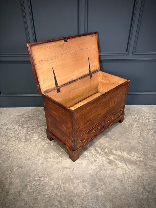 fig 2. A Georgian elm blanket box featuring a hinged top lid, two lower drawers with brass swan-neck handles, and shaped bracket feet.
