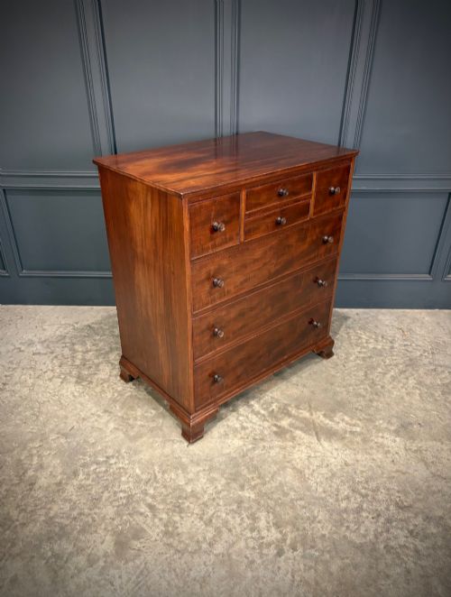 fig 1. A tall antique mahogany chest of drawers featuring an upper arrangement of small drawers over three graduated full-width drawers, resting on bracket feet.