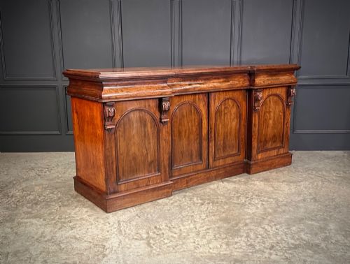 fig 1. A Victorian mahogany four-door breakfront sideboard featuring arched panel doors, carved support brackets, and a long flat top surface.