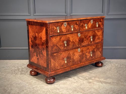 fig 1. A seventeenth-century kingwood chest of drawers featuring geometric oyster veneering, brass teardrop handles, and turned bun feet.
