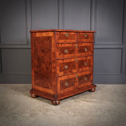 fig 1. A 17th-century William and Mary chest of drawers featuring geometric oyster veneer, boxwood stringing, brass drop handles, and turned bun feet.