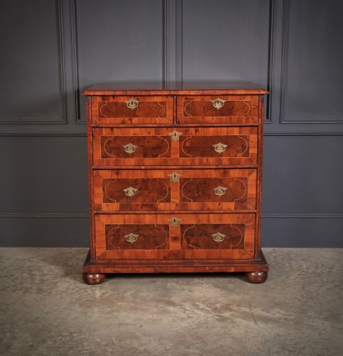 fig 2. A 17th-century William and Mary chest of drawers featuring geometric oyster veneer, boxwood stringing, brass drop handles, and turned bun feet.