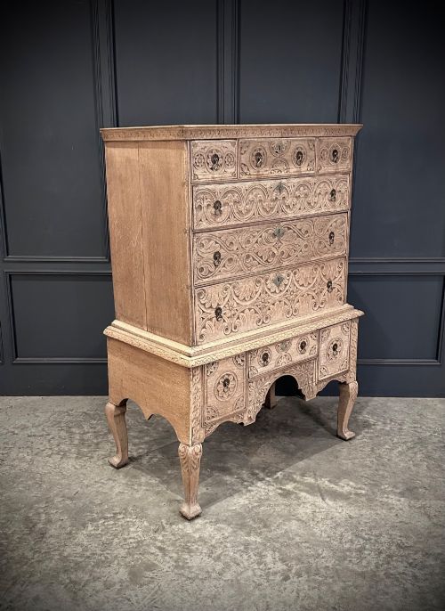 fig 1. An 18th-century bleached oak chest on stand featuring carved foliage motifs across the drawer fronts and elevated on cabriole legs.